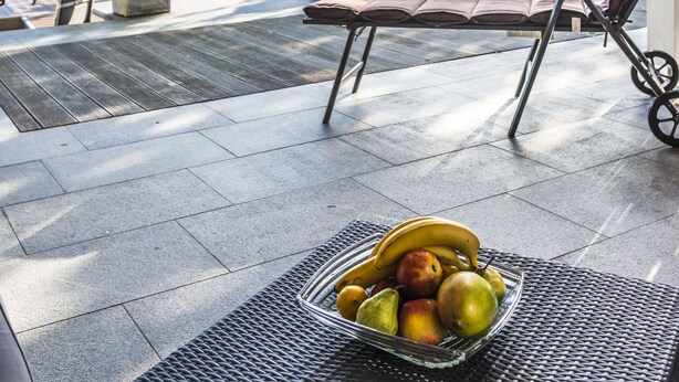 Un espacio de estar al aire libre techado con vista a un lago, un velero y una torre a lo lejos.