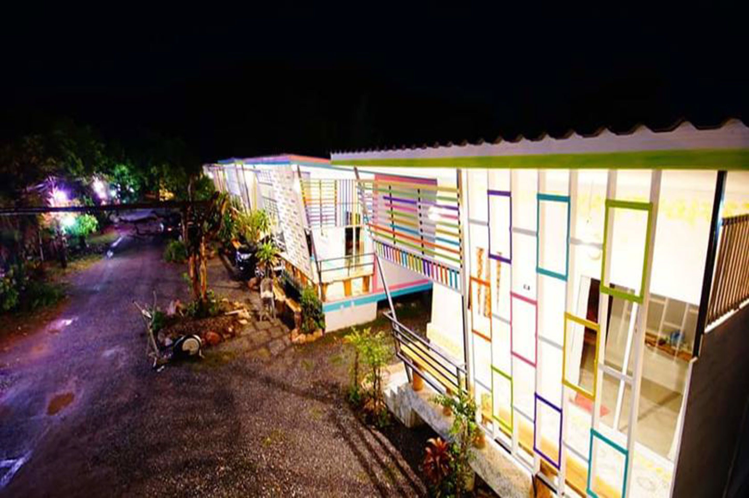 A row of brightly lit, colorful cabins with a gravel path leading to them.