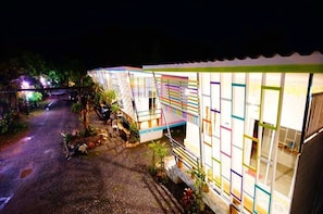 A row of brightly lit, colorful cabins with a gravel path leading to them.