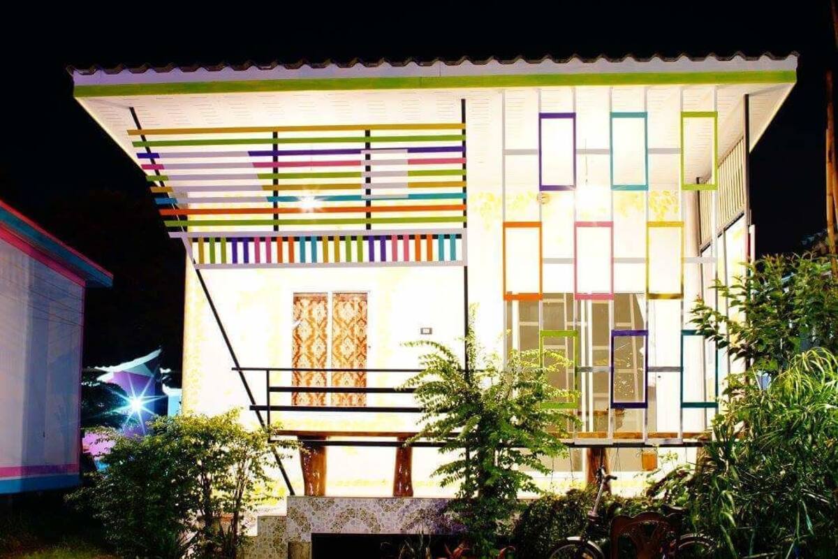 A modern building with a flat roof, large windows, and a balcony with colorful railings.