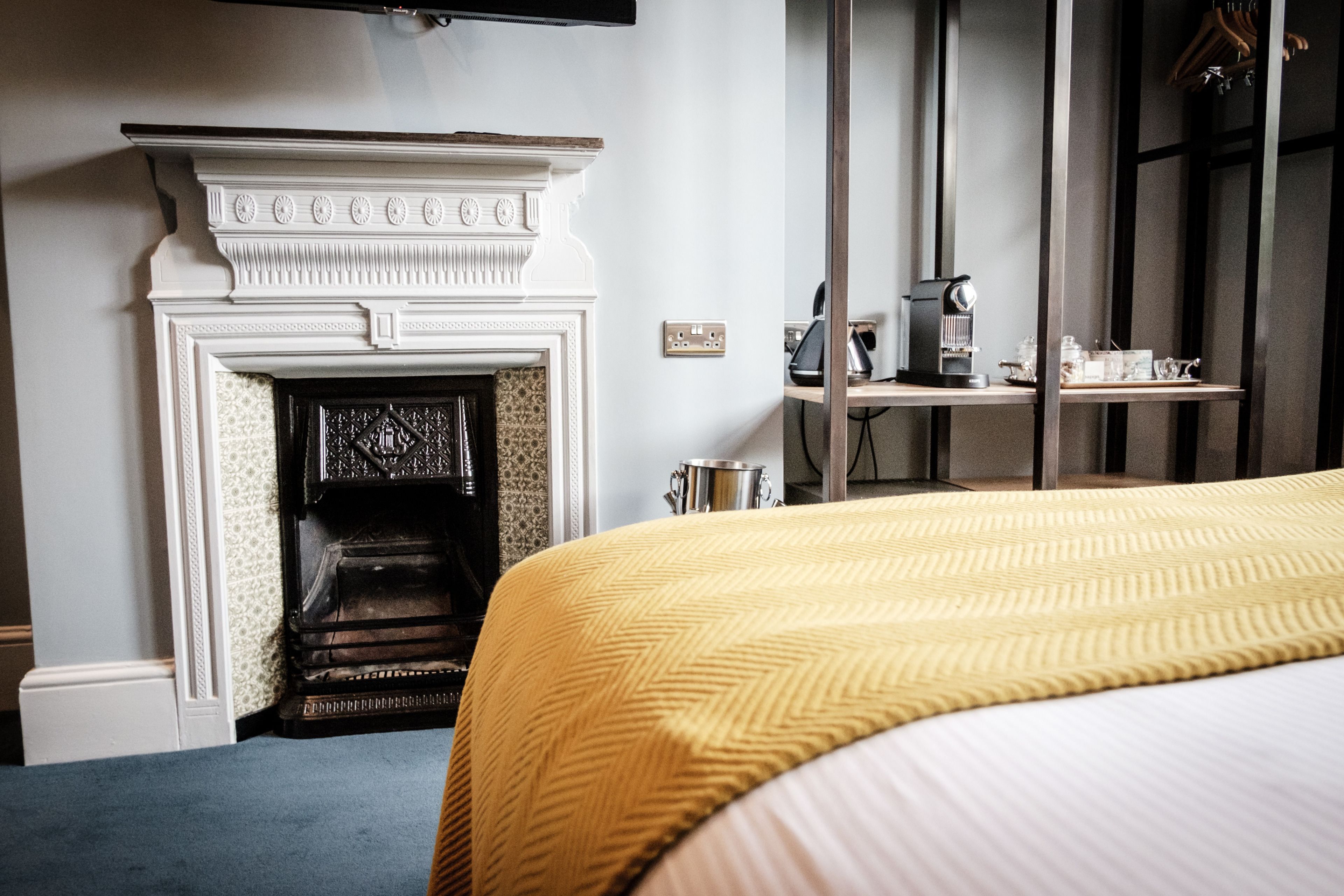 Ein Hotelzimmer mit einem Bett, einem Kamin, einer Kaffeemaschine und einem Regal mit Gegenständen.