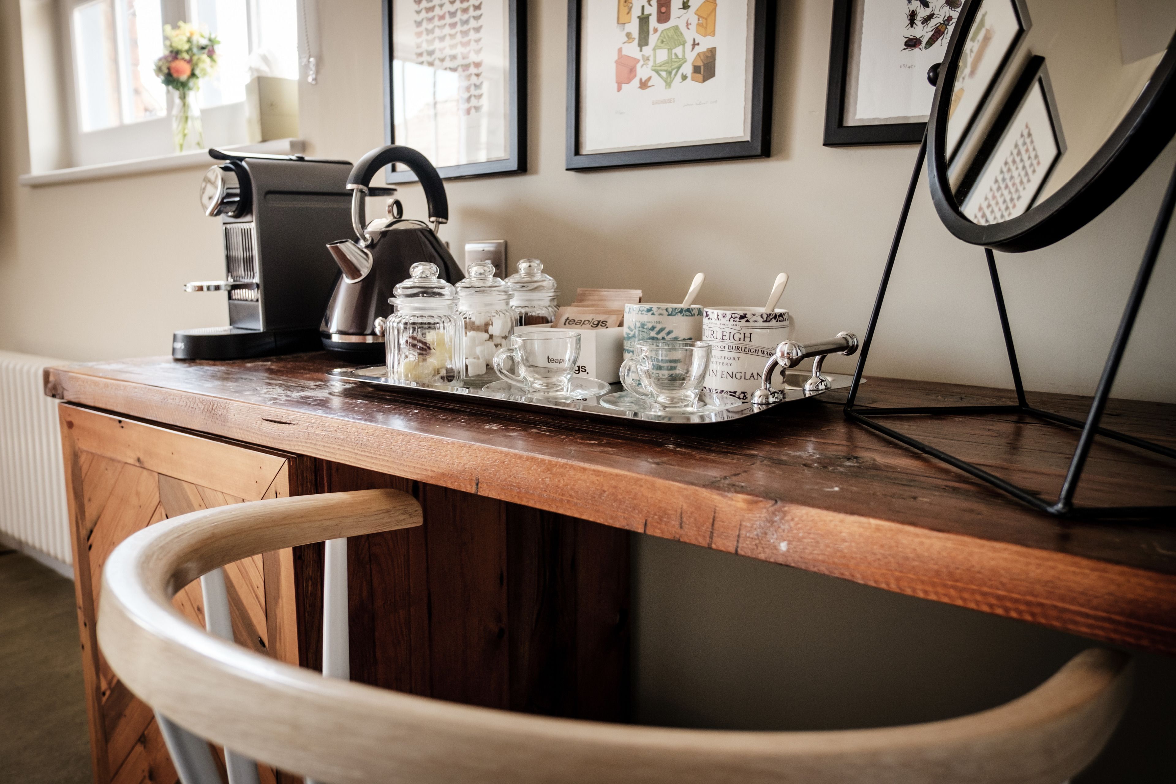 A wooden bar counter with a coffee machine, jars, and glasses.