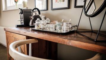 A wooden bar counter with a coffee machine, jars, and glasses.