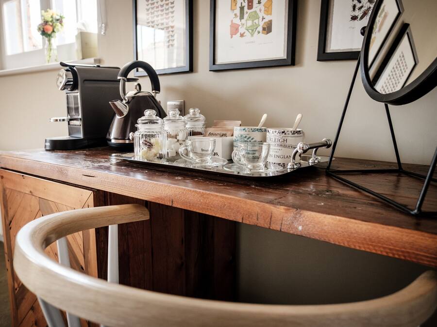 A wooden bar counter with a coffee machine, jars, and glasses.