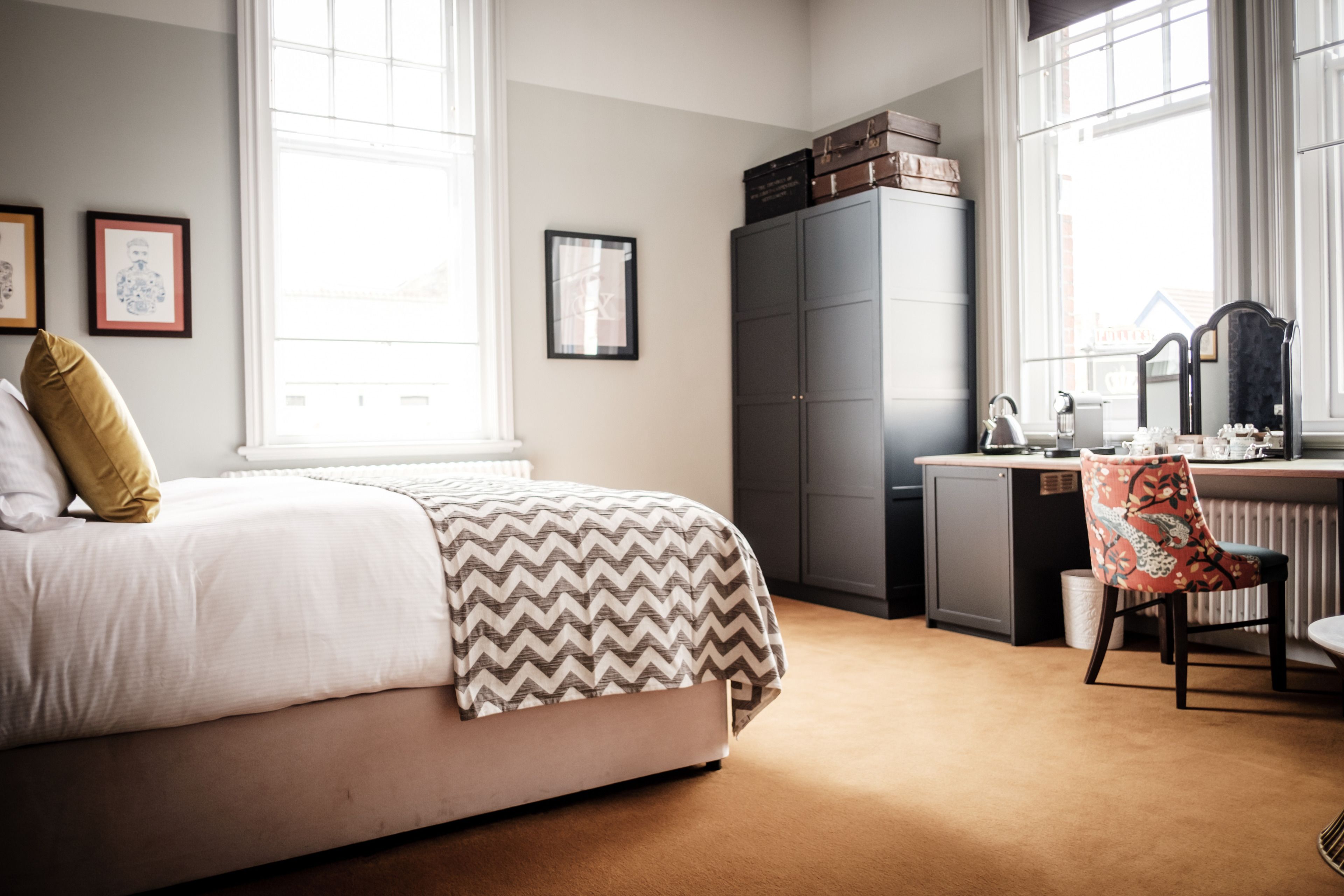 A bedroom with a bed, a desk, a chair, and a radiator.