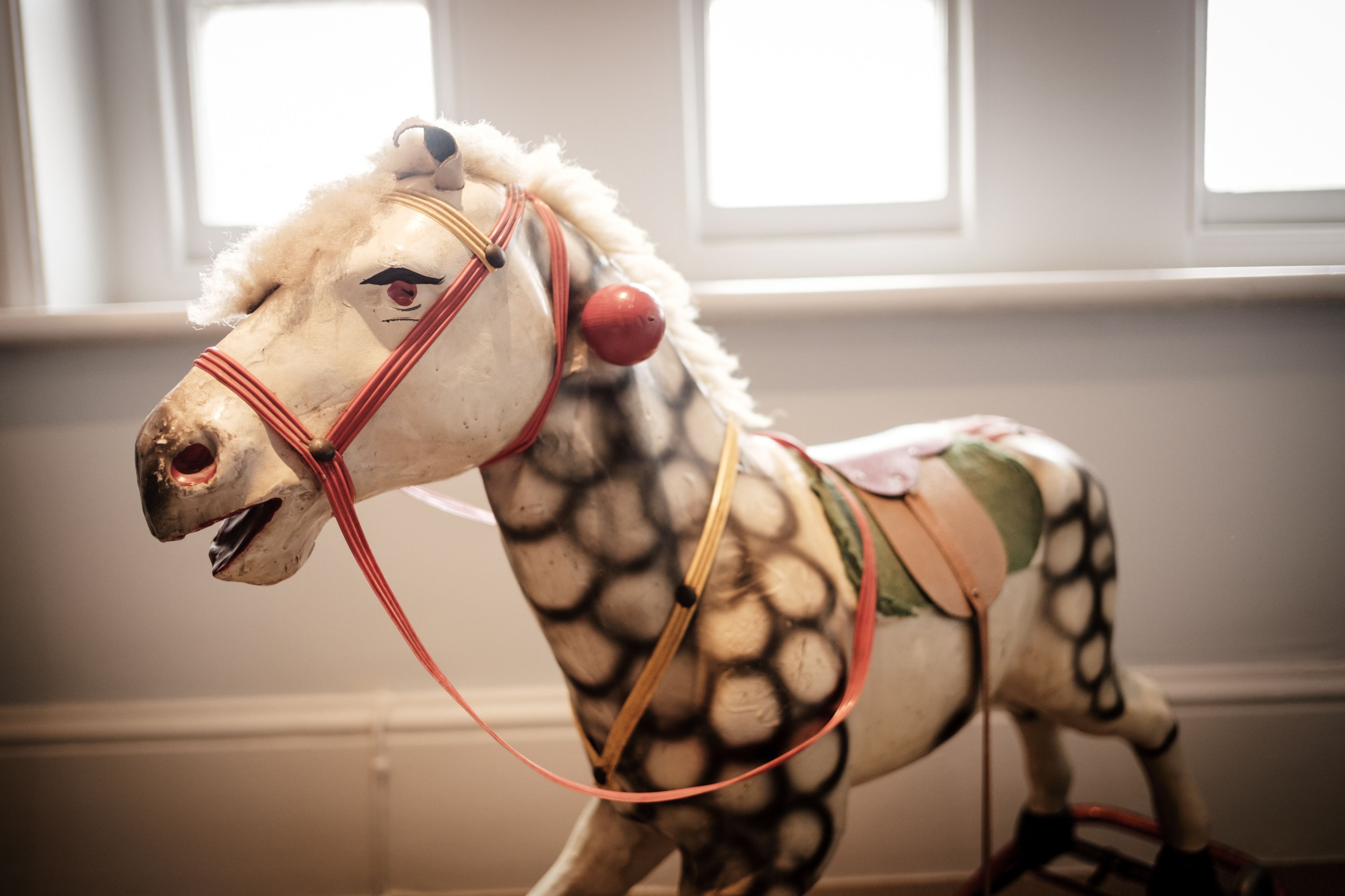 A carousel horse with a white mane and red bridle.