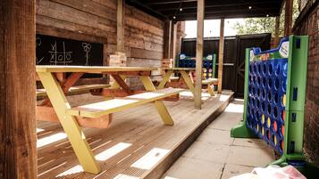 A wooden outdoor seating area with picnic tables and a children's play structure.