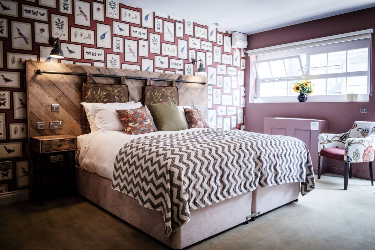 A bedroom with a wooden headboard, a patterned bedspread, and a wall decorated with framed bird illustrations.