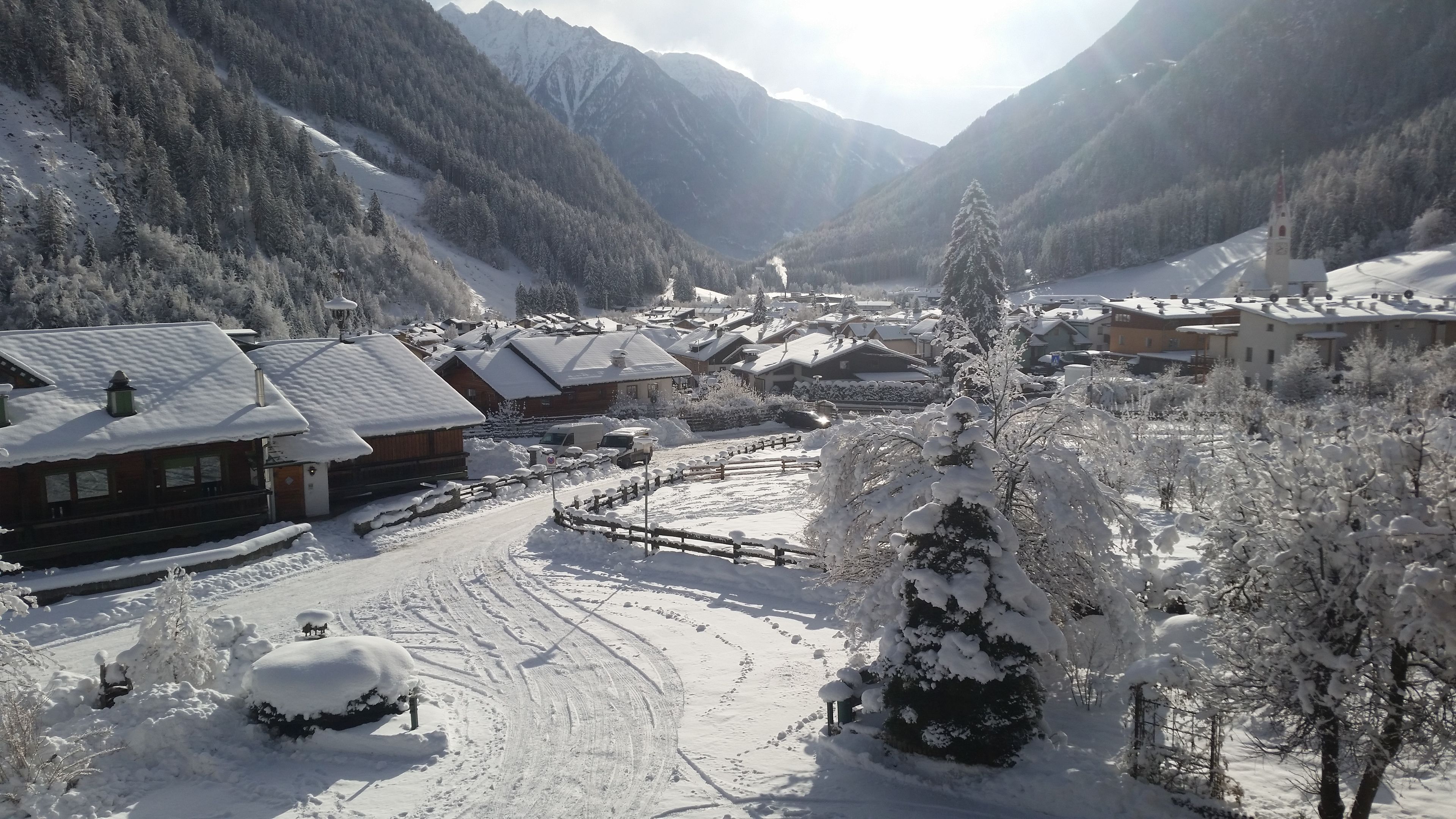 Un pueblo en la montaña cubierto de nieve con edificios de madera, una iglesia y una vista despejada del valle.