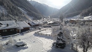A snow-covered mountain village with wooden buildings, a church, and a clear view of the valley. - Hotel Schwarzbachhof (Valle Aurina)