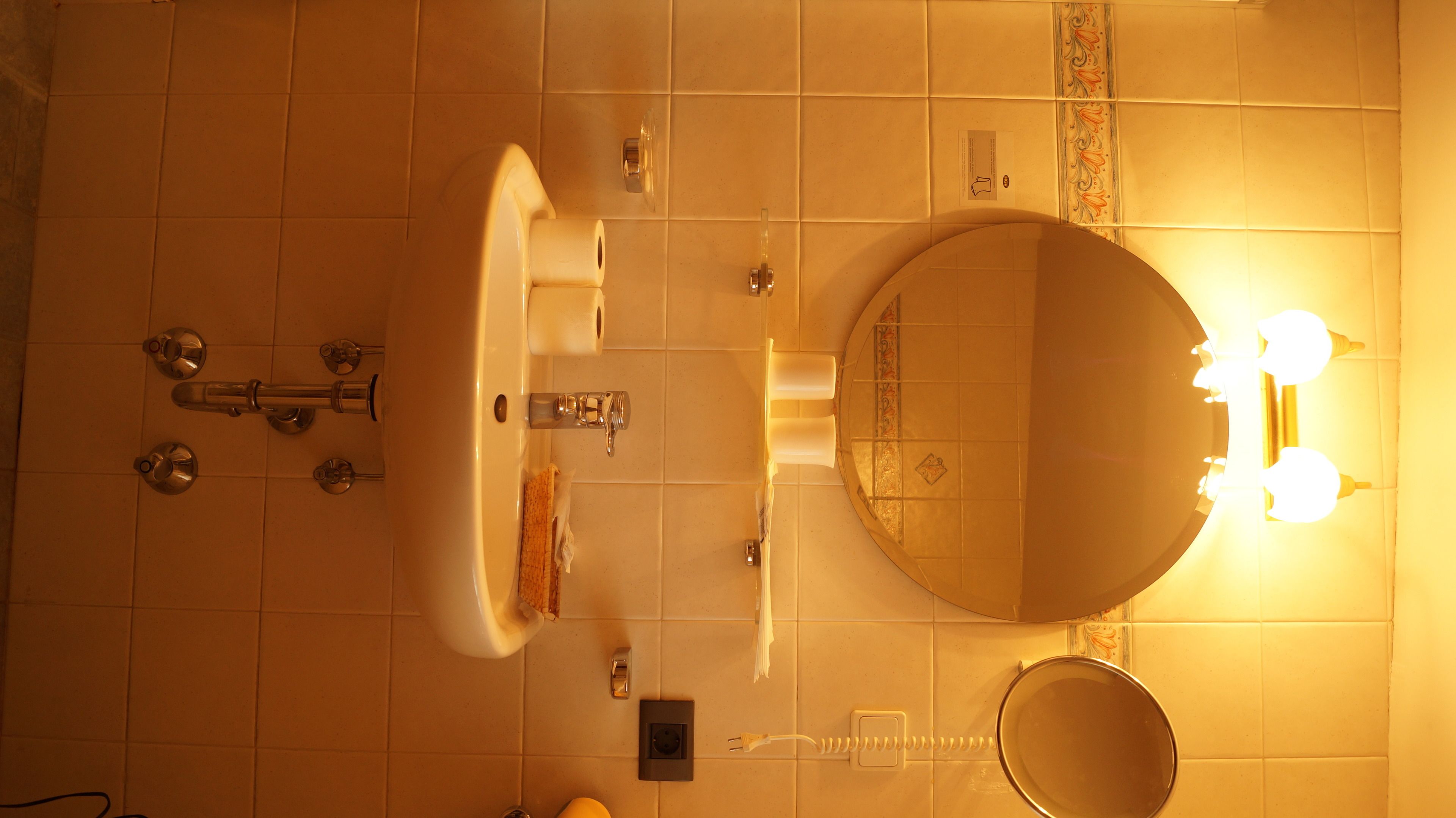 A bathroom with a sink, mirror, and light fixture.