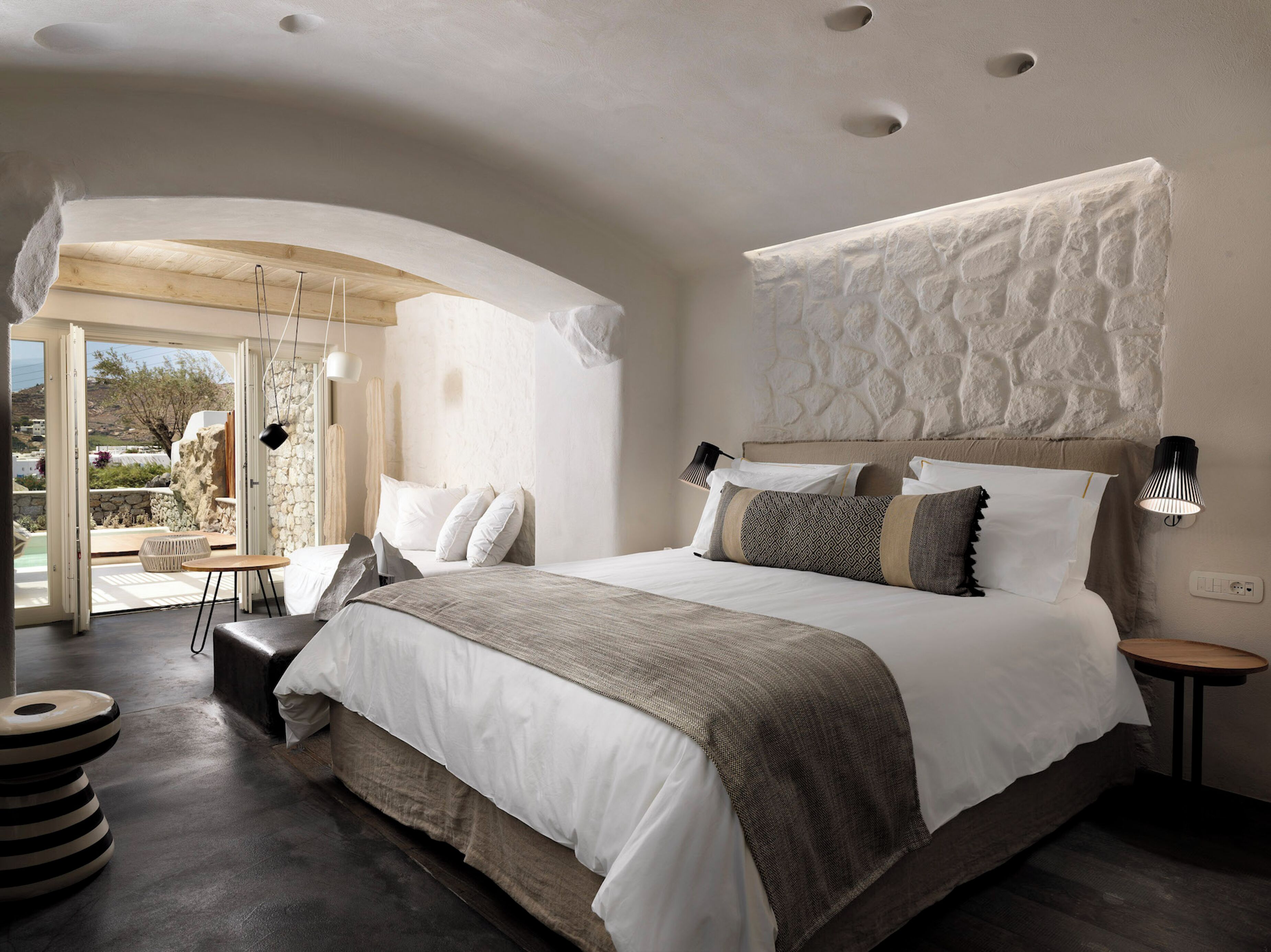 Ein modernes Schlafzimmer mit einem großen Bett, einer Sitzecke und Blick ins Freie.