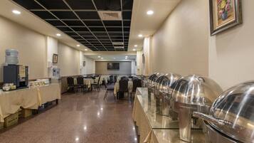 A buffet setup with multiple food stations, tables, chairs, and water dispensers.