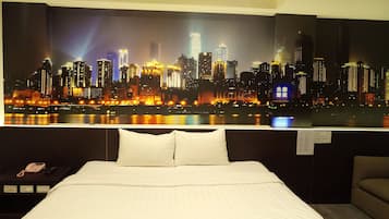 A hotel room with a large cityscape view, a bed with white linens, a bedside table with a phone, and a chair.