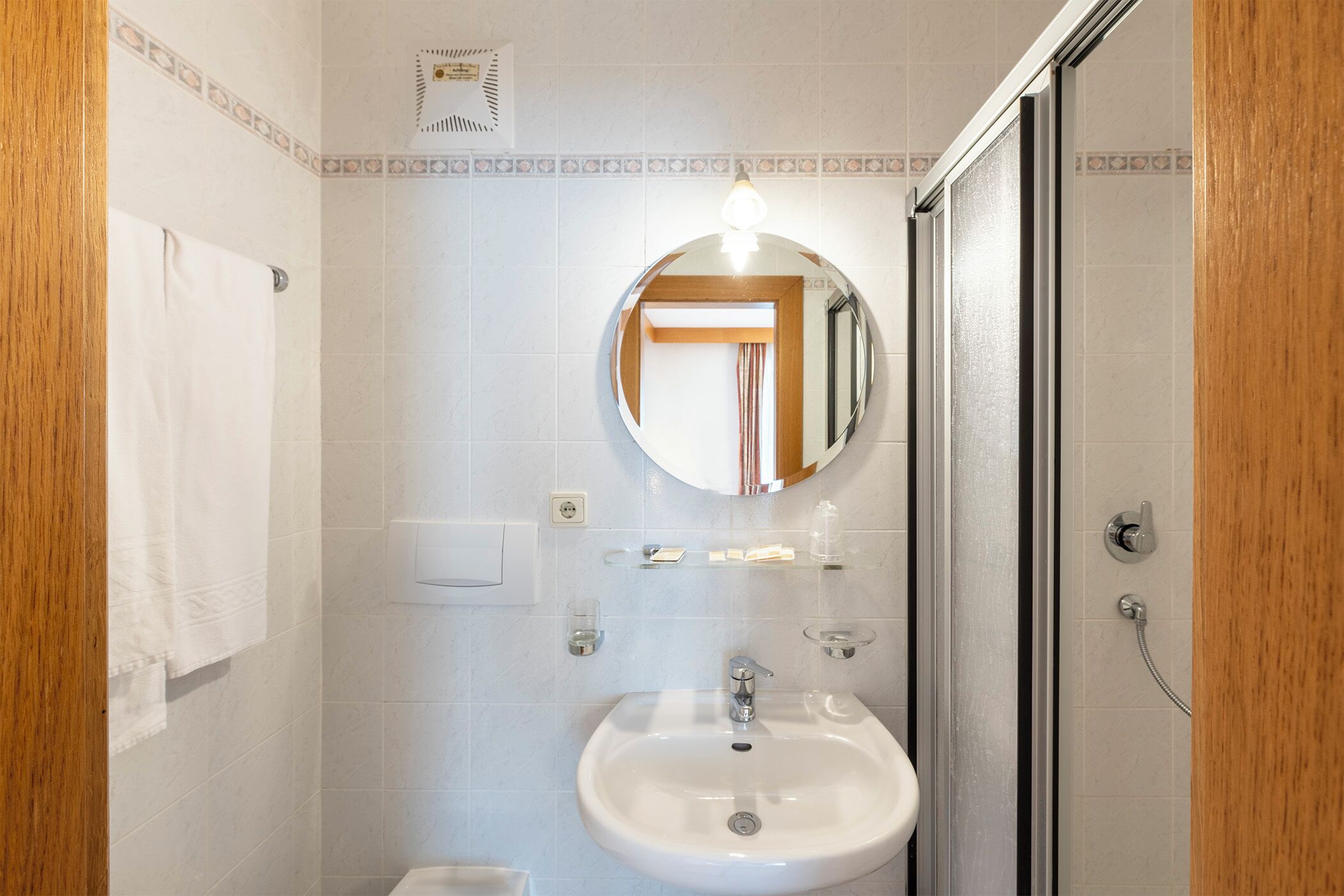 Un baño con lavamanos blanco, un espejo y ducha.