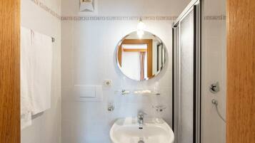 Un baño con lavamanos blanco, un espejo y ducha.