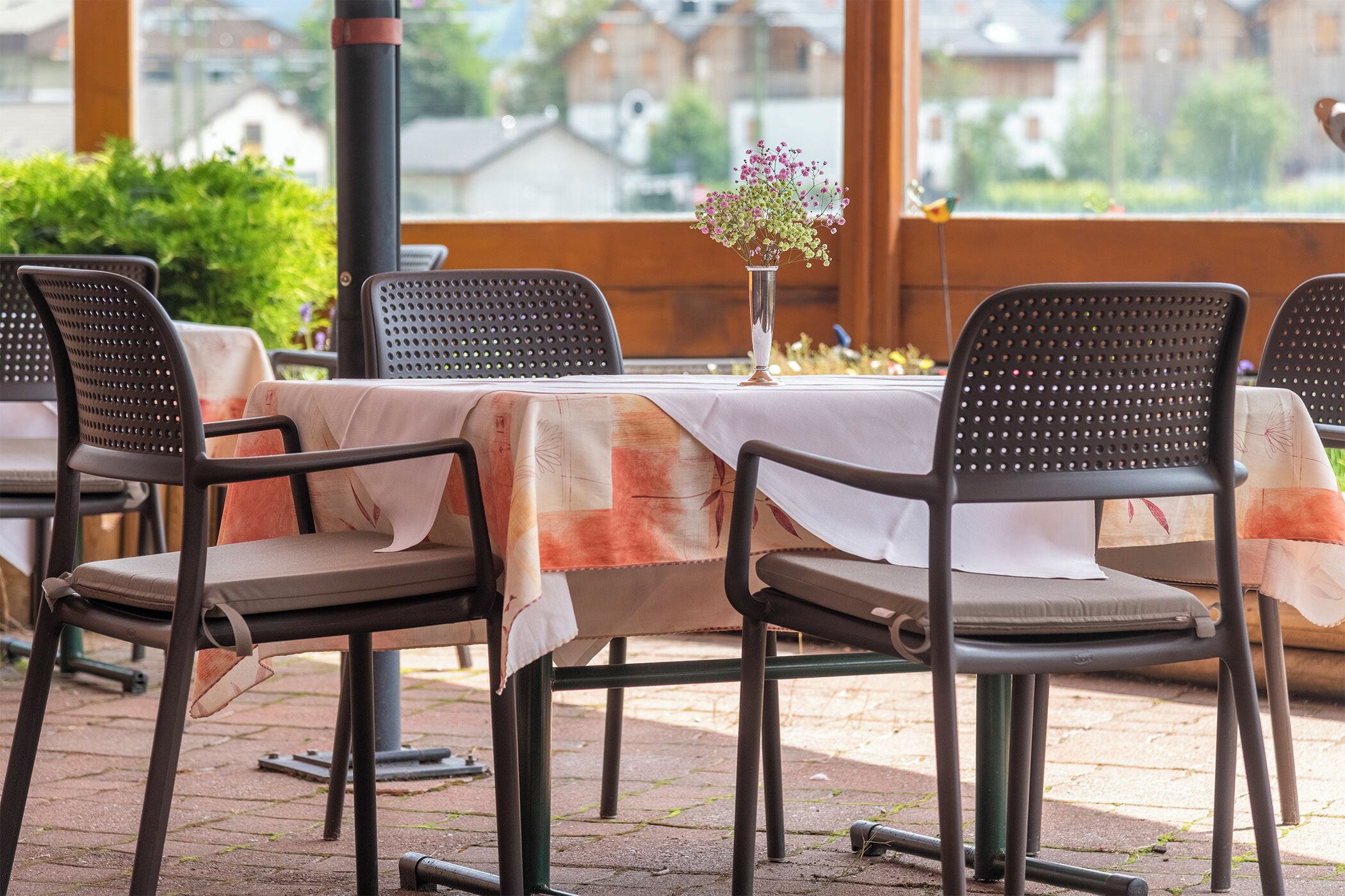 Un área de comedor al aire libre con sillas de metal y una mesa cubierta con mantel blanco.
