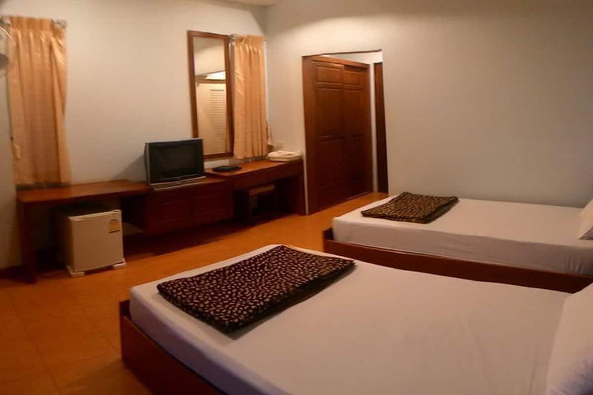 Habitación de hotel con dos camas, un escritorio con televisor, armario y refrigerador pequeño.