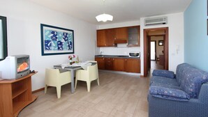 Un espacio habitable compacto con comedor, kitchenette y sofá.