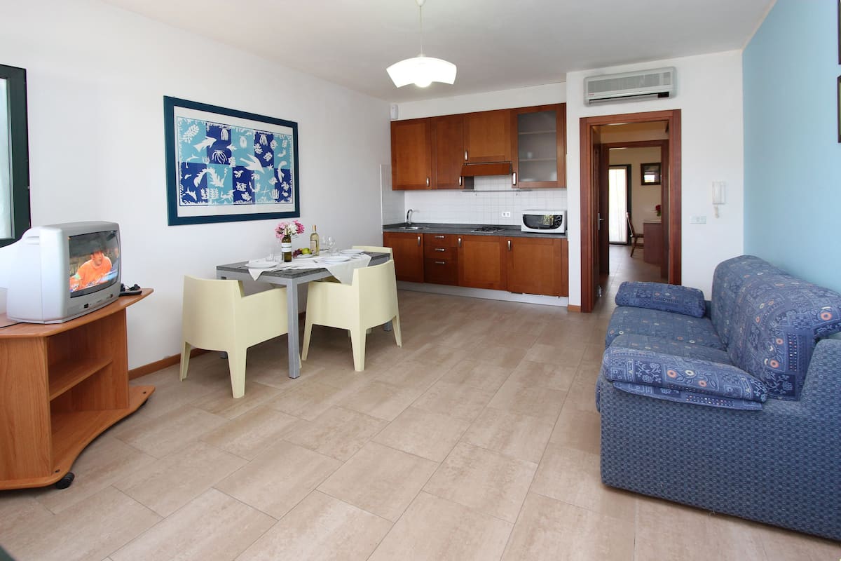 Un espace de vie compact comprenant un coin repas, une kitchenette et un canapé.