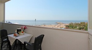 A balcony with a table and chairs, overlooking a beach with a clear view of the sea and a lifeguard tower. - Eurobeach Residence (Cavallino-Treporti)