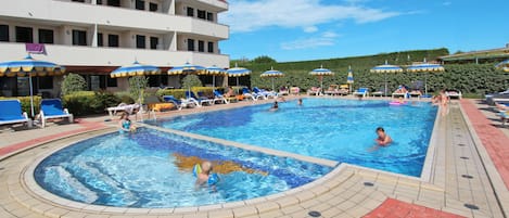 A hotel pool area with multiple pools, sun loungers, and umbrellas.