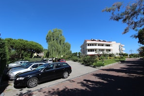 Guests can park their vehicles in the paved lot adjacent to the building, surrounded by lush greenery.