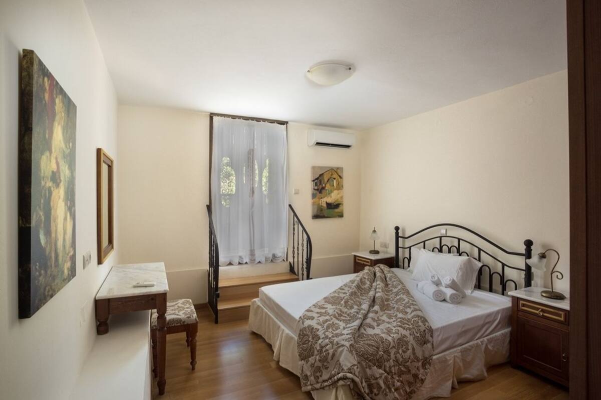 Un dormitorio con cama, escritorio, silla, escalera y un cuadro en la pared.