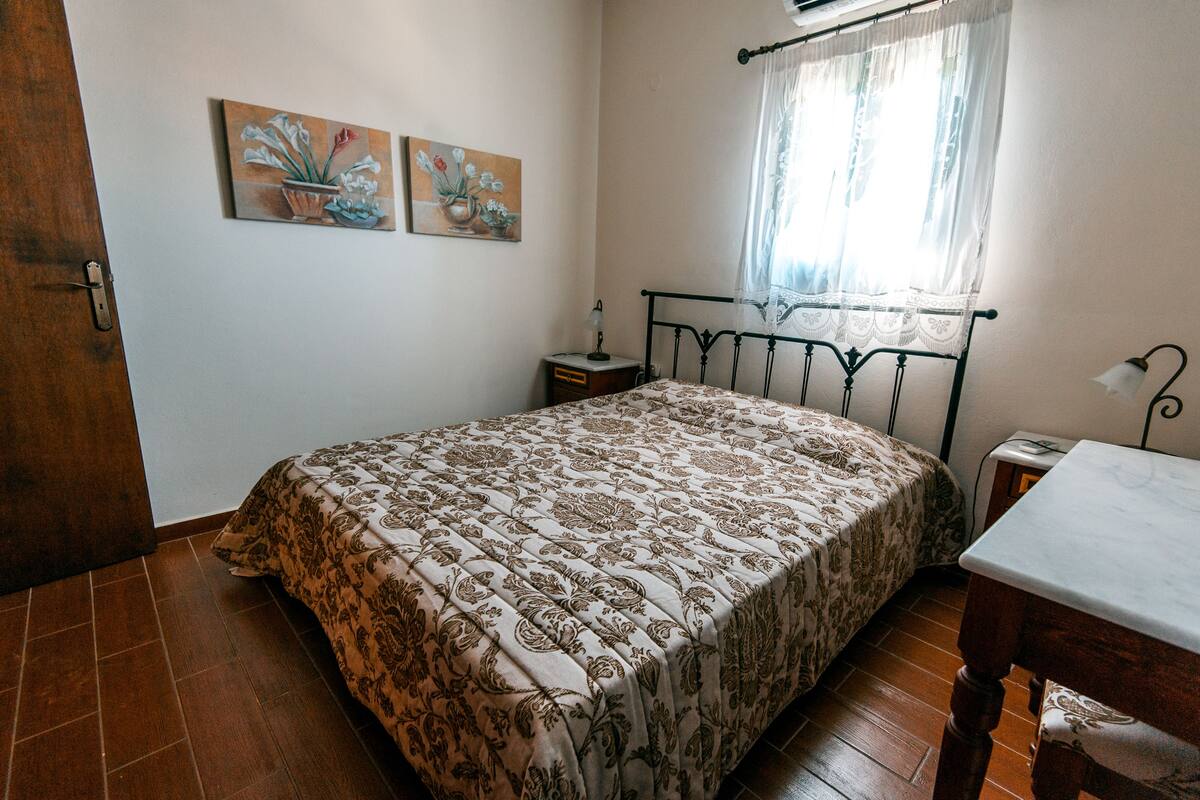 Un dormitorio con una cama, una mesita de noche, una mesa y dos cuadros en la pared.