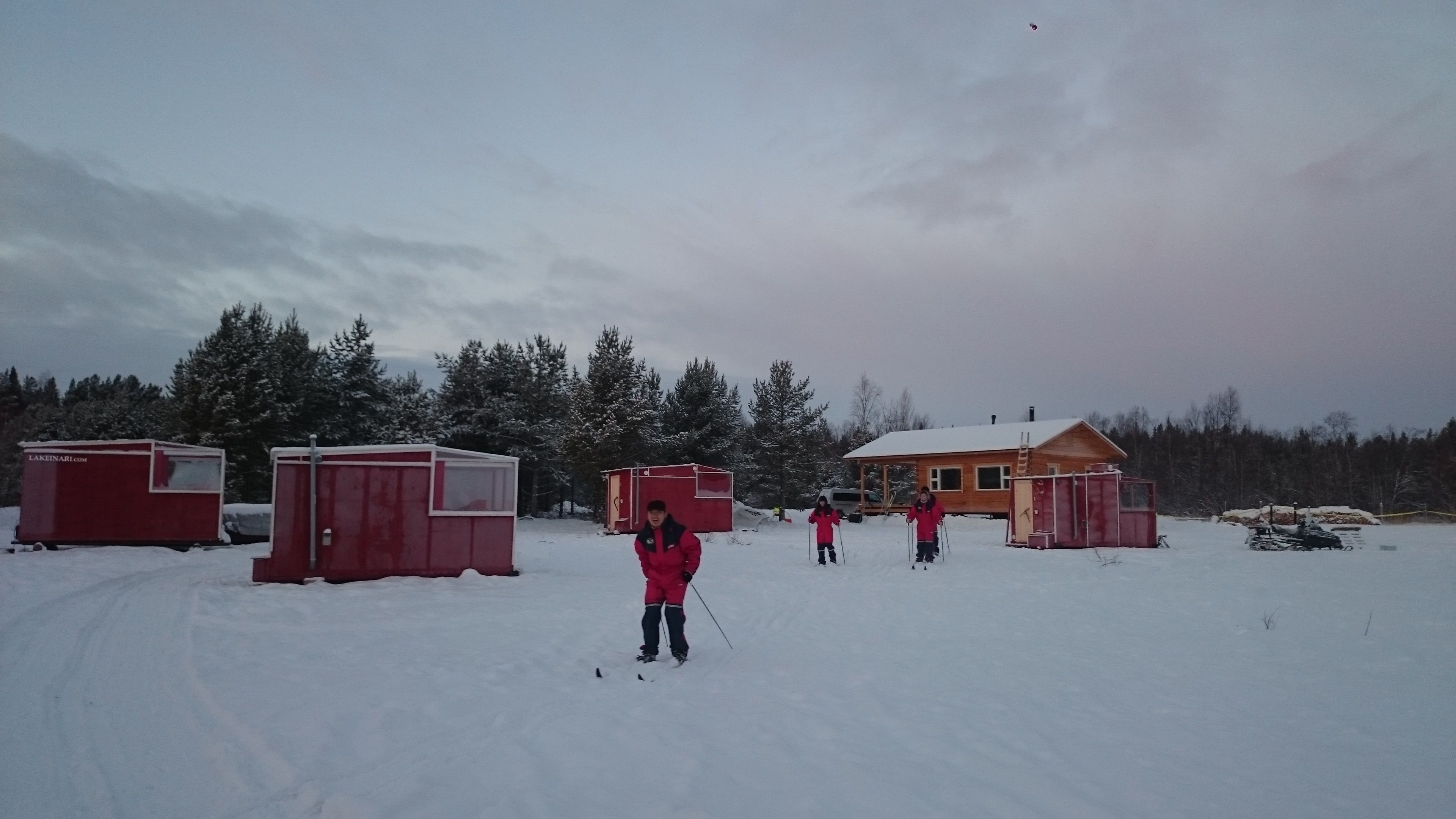 Un paysage enneigé avec plusieurs cabanes rouges et une maison en bois.