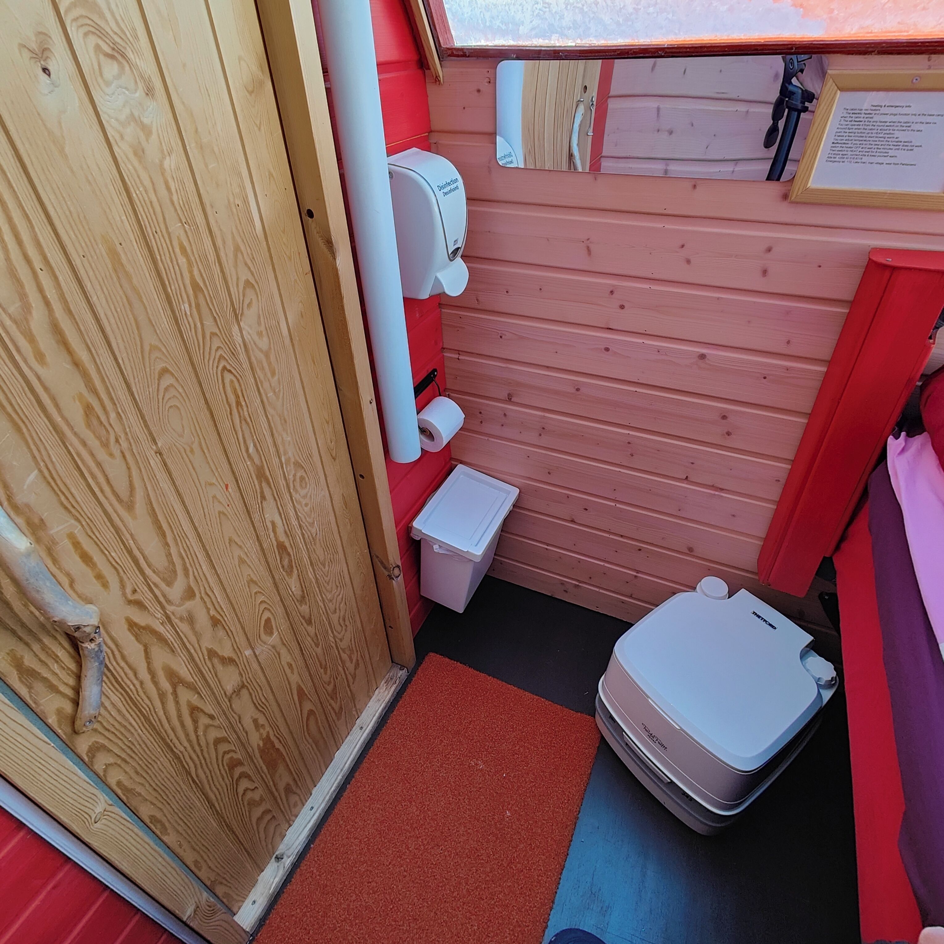 A compact bathroom with a wooden door, a toilet, a small sink, and a shower area.