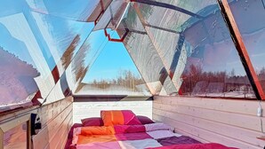 A cozy cabin with a bed, a window, and a view of a snowy landscape.
