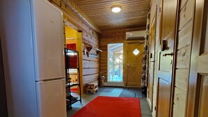 A narrow hallway with wooden walls and a tiled floor, leading to a door at the end.
