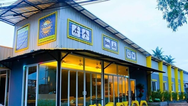 Un edificio con un letrero que dice "Room Restaurant" e íconos que señalan servicios como piscina y gimnasio.