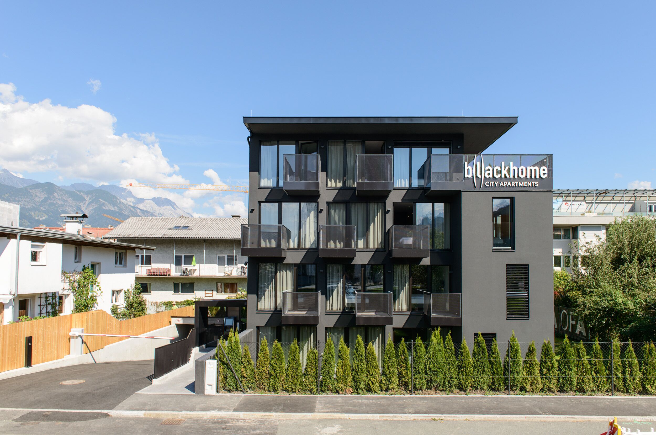 Een modern meerlaags gebouw met balkons, genaamd 'Blackhome City Apartments', met een eigentijds architectuurontwerp.