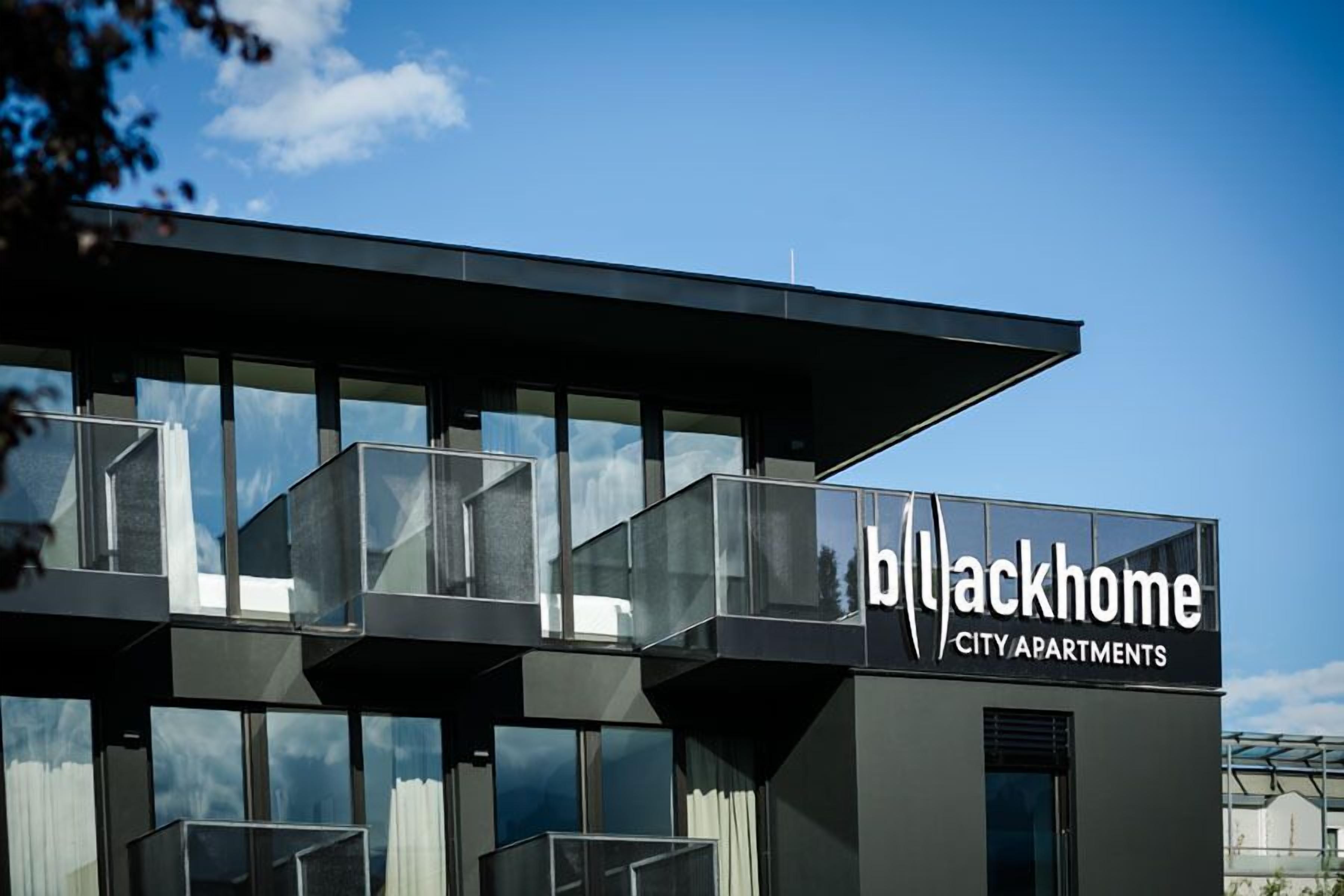 Un immeuble moderne doté de balcons et d’une enseigne indiquant « Blackhome City Apartments ».