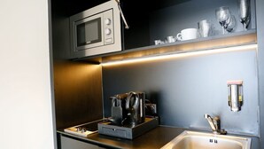 A compact kitchenette with a microwave, coffee maker, and sink.