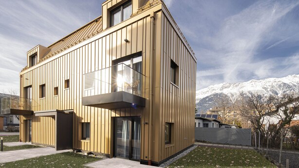 A modern two-story building with a sloped roof, large windows, and a balcony.