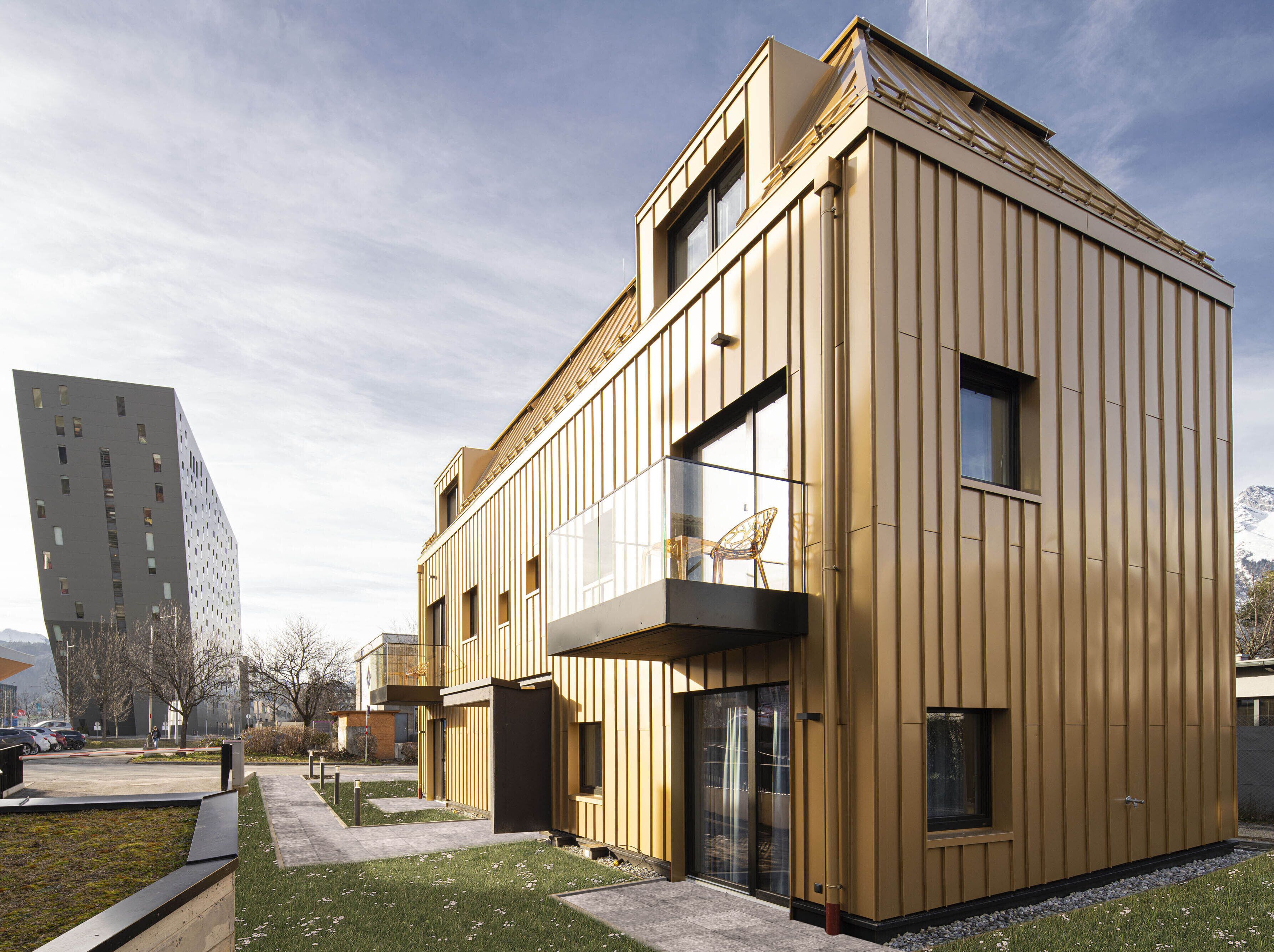 A modern building with a flat roof, large windows, and a balcony.