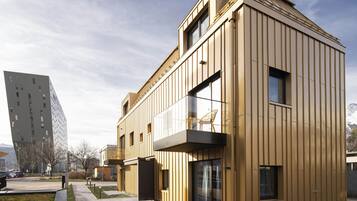 A modern building with a flat roof, large windows, and a balcony.