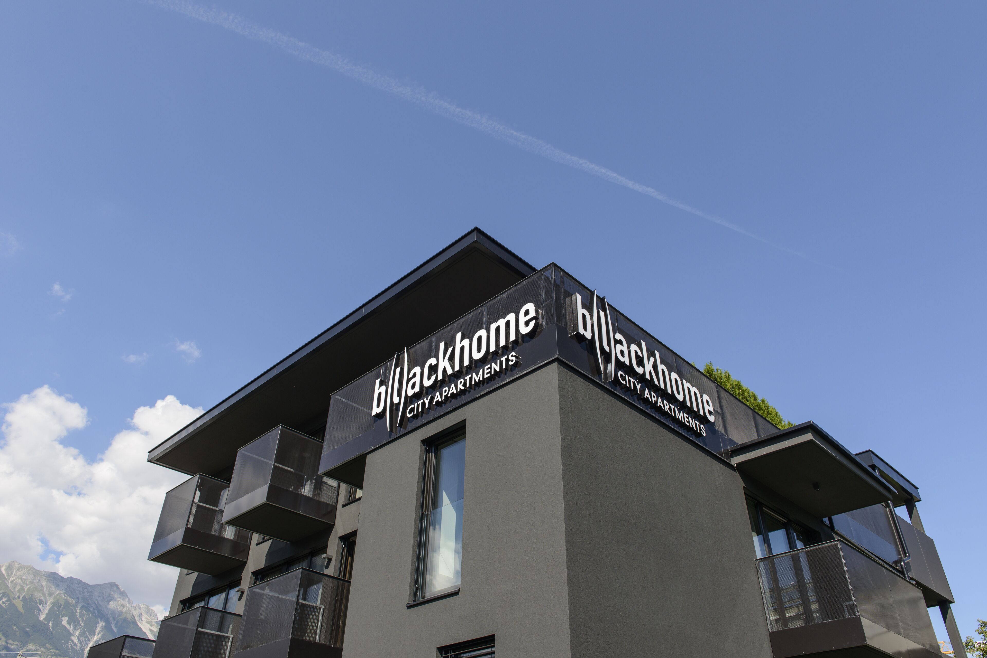 A modern building with balconies and a sign reading "Blackhome City Apartments".