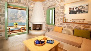 Une pièce chaleureuse avec un mur en pierre, une cheminée, un canapé et une table sur laquelle se trouve un panier rempli de divers objets.