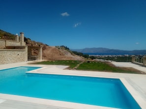 A swimming pool with a clear view of a mountainous landscape and a distant town. - Villa Stylianos - Hostel (Kissamos)
