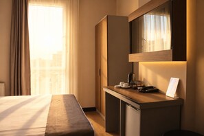 A hotel room with a bed, a desk with a phone, a coffee maker, and a small cabinet. - Niconya Port Suite&Hotel (Istanbul)
