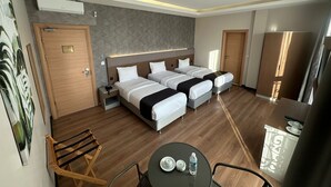 Quarto de hotel com duas camas, uma escrivaninha, uma cadeira, uma mesa com uma garrafa e um espelho.