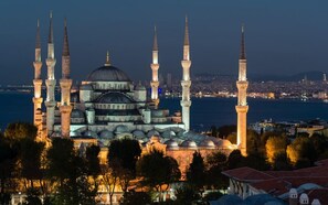 A historic mosque with multiple minarets and domes, surrounded by trees and overlooking a body of water. - Niconya Port Suite&Hotel (Istanbul)