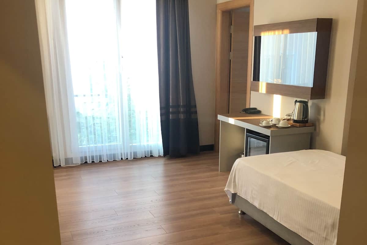 A hotel room with a bed, desk, and a view of the outdoors.