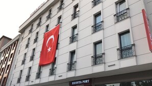 Um hotel com uma grande bandeira turca, varandas e uma placa indicando o Hotel Niconya Port Suite.