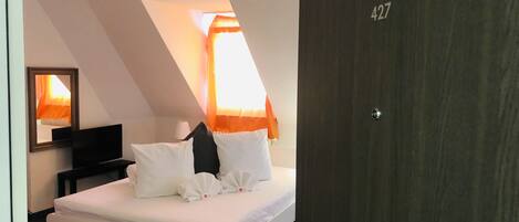 A hotel room with a bed, a TV, and a door with the number 427.