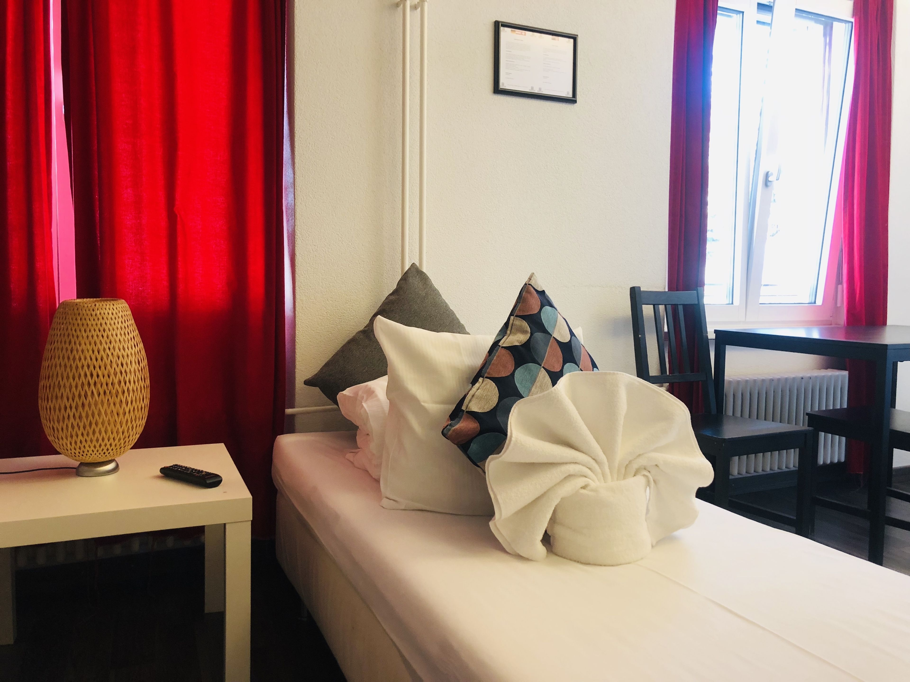 A hotel room with a bed, a desk, a lamp, and a chair.